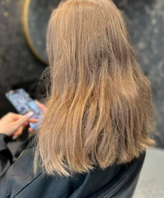 Cheveux blond foncé mi-longs, vue de dos, au salon