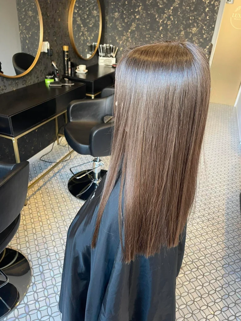 Longs cheveux châtains, lisses et brillants, au salon