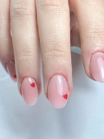 Ongles nude ornés de petits cœurs rouges