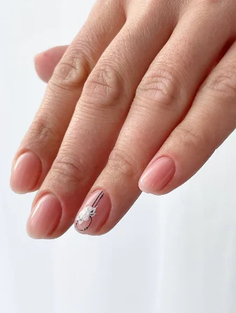 Ongles nude, un ongle décoré d’une fleur blanche